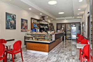 une boulangerie avec des chaises rouges et un comptoir avec des pâtisseries dans l'établissement Hotel Al Castello, à Pomezia