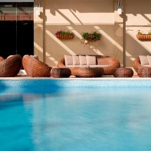 a swimming pool with wicker chairs and blue water at Congo Palace in Athens