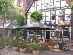 un grupo de personas sentadas en un restaurante bajo un paraguas en Hotel Zum Weißen Roß, en Winsen