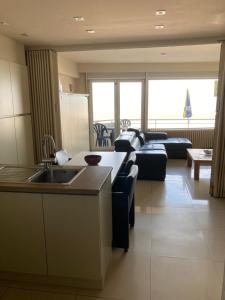 een keuken en een woonkamer met een bank en een wastafel bij "Puerto Cristo G2" - Modern Studio with Seaview in Oostende