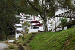 a large white building with red umbrellas on a hill at The Pines at Fraser's Hill, Malaysia in Bukit Fraser