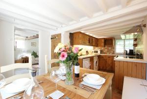 a kitchen with a wooden table with a vase of flowers at Honeysuckle Cottage- East Meon in East Meon