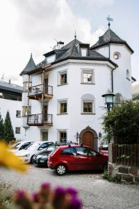 a white building with cars parked in front of it at Residence Castel in Ortisei