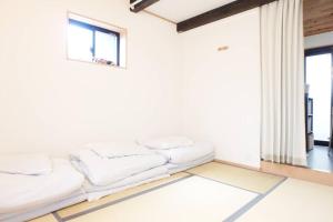 een witte kamer met 2 bedden en een raam bij Higashimonzen in Kyoto