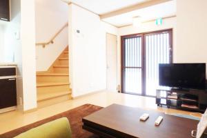 een woonkamer met een tv en een bank en een tafel bij Higashimonzen in Kyoto