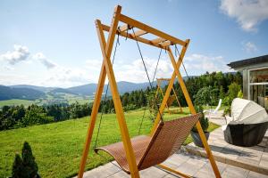 a swing on a patio with a view at Richterhof Wellness Apartments Bayerischer Wald in Kollnburg