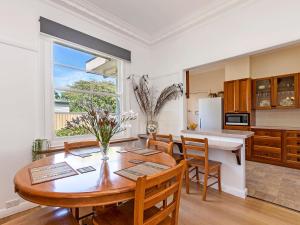a kitchen and dining room with a wooden table and chairs at Bloom on Sackville Opt1 in Port Fairy