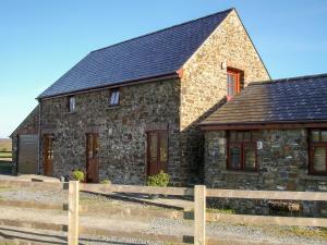 una casa de piedra con una valla de madera delante de ella en The Hagguard, en Kilgetty