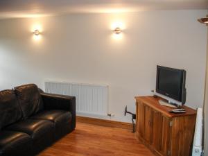 a living room with a couch and a flat screen tv at The Hagguard in Kilgetty