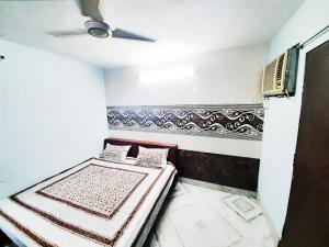 Habitación pequeña con 2 camas y ventilador de techo. en AMAN RESIDENCY en Nueva Delhi