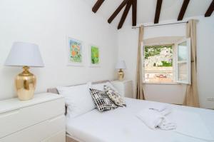 a white bedroom with a white bed and a window at Cinema View House in Dubrovnik