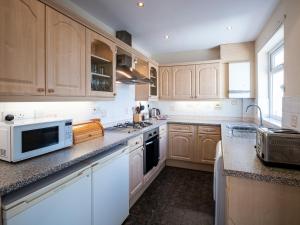 a kitchen with wooden cabinets and white appliances at Bryn Y Mor in Colwyn Bay