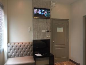 a hotel room with a couch and a tv on the wall at Chics Resort ชิคส์รีสอร์ท in Ban Khlong Nung