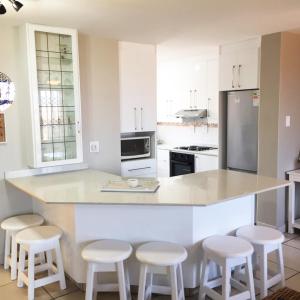 a kitchen with white cabinets and a counter with stools at Villa Siesta Flat No.8 in Margate