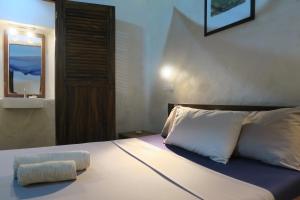 Schlafzimmer mit einem Bett mit einem Kissen und einem Spiegel in der Unterkunft Cafe Central in Ilha de Moçambique
