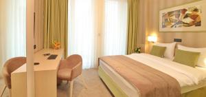 ein Hotelzimmer mit einem großen Bett und einem Schreibtisch in der Unterkunft Hotel Argo in Belgrad