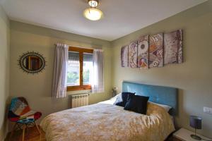 1 dormitorio con cama, ventana y silla en Nuevo - Cómodo y coqueto chalet con jardín en Argoños en Argoños
