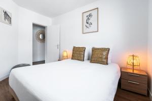 um quarto com uma grande cama branca e 2 candeeiros em DORMIR A CLERMONT-FERRAND - Safari em Clermont-Ferrand