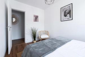 une chambre blanche avec un lit et une chaise dans l'établissement DORMIR A CLERMONT-FERRAND - Safari, à Clermont-Ferrand 32 autres photos