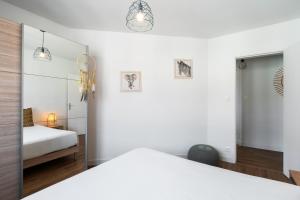 une chambre blanche avec un lit et un miroir dans l'établissement DORMIR A CLERMONT-FERRAND - Safari, à Clermont-Ferrand