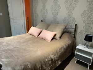 ein Schlafzimmer mit einem Bett mit zwei rosa Kissen in der Unterkunft La Maison Clémenso in Cluny