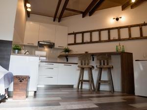 una cocina con armarios blancos y 2 taburetes en Apartman Vulcano, en Zvolen