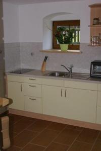 een keuken met witte kasten, een wastafel en een raam bij Ferienwohnung Wagner in Kurort Altenberg