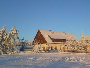 a barn covered in snow with trees and a fence at Ferienwohnung Wagner in Kurort Altenberg