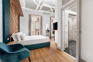 1 dormitorio con 1 cama y 1 silla azul en Elys Suites en Sorrento