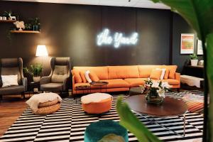 uma sala de estar com um sofá laranja e cadeiras em The Yard Hostel em Helsinque