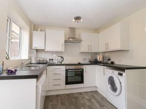 a kitchen with white cabinets and a washer and dryer at Littledown in Bournemouth