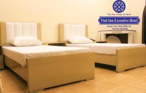 twee bedden naast elkaar in een kamer bij Hotel Visit Inn Executive in Lahore