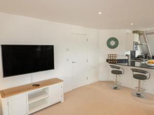 uma cozinha branca com uma televisão de ecrã plano na parede em Stores & Supplies em Bodmin