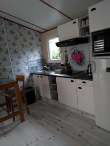 a kitchen with white cabinets and a table and a window at le haut village Chambre d'hôtes Mobi-Loft cosy sauna ,douche ,chromothérapie in Arrest