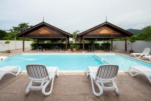 a swimming pool with two chairs and a table at Riverra Inn Langkawi in Kuah