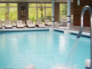 a swimming pool with lounge chairs in a building at Les Appartements du Parc - Accès piscine et spa in Munster