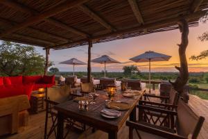 un tavolo da pranzo con sedie e ombrelloni su un patio di Baobab Ridge a Klaserie Private Nature Reserve