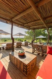 una terrazza in legno con tavolo, sedie e ombrelloni di Baobab Ridge a Klaserie Private Nature Reserve