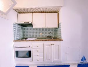 a small kitchen with white cabinets and a sink at Marina Cap Monastir- Appart'Hôtel in Monastir