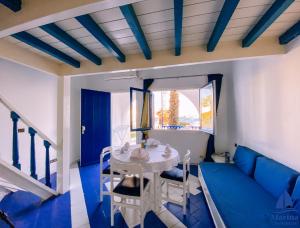 a blue and white living room with a table and chairs at Marina Cap Monastir- Appart'Hôtel in Monastir