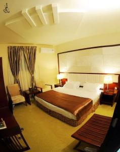 una habitación de hotel con una cama grande y una silla en Al Ebreez Palace, en Buraidah