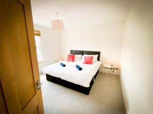 um quarto com uma cama com lençóis brancos e almofadas vermelhas em Nomi Homes - Powderham - Exeter - Uni - Free parking - Central em Exeter