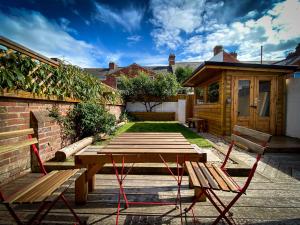 エクセターにあるNomi Homes - Powderham - Exeter - Uni - Free parking - Centralの庭のピクニックテーブルとベンチ2脚