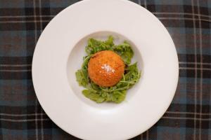 a white plate with a food item on top of greens at The Crown Guest House in East Linton