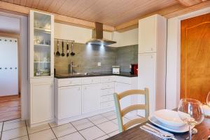eine Küche mit weißen Schränken und einer Holzdecke in der Unterkunft Chez Marie-Claude in Vendlincourt