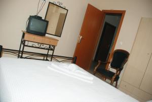 Schlafzimmer mit einem Bett, einem TV und einem Spiegel in der Unterkunft Villa Maria in Ierissós