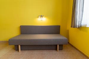 a bench in a room with a yellow wall at Izabella Panzio in Hajdúszoboszló