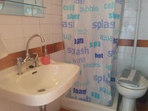 a bathroom with a sink and a toilet and a shower curtain at Perdika Mare Guesthouse in Perdika