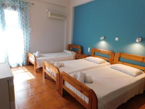 a bedroom with two beds and a blue wall at Perdika Mare Guesthouse in Perdika