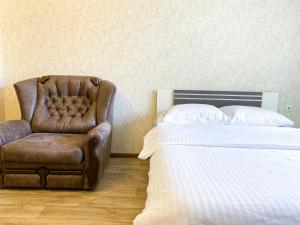 a bedroom with a bed and a leather chair at ApartPoltava Простора однокімнатна квартира в НОВОМУ будинку в самому серці Полтави, Банківський ЧЕК in Poltava +12 photos